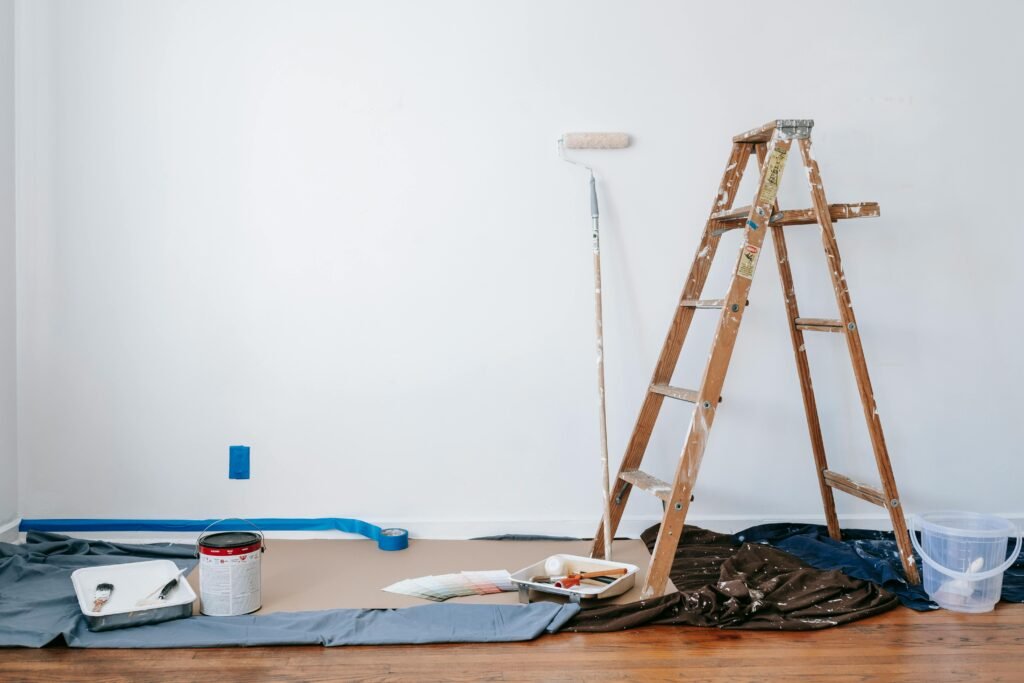 pexels photo 7218525 7218525 A room prepared for renovation with a ladder, paint supplies, and drop cloth.